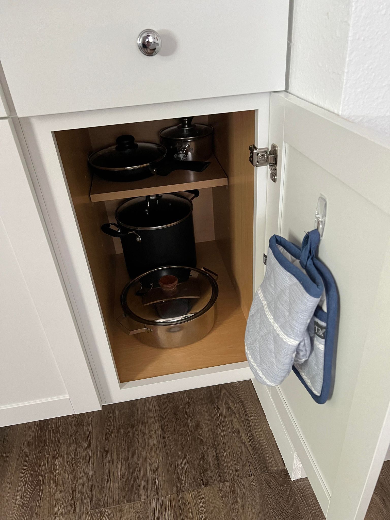 A kitchen with two pots on shelves and a hanging cloth.