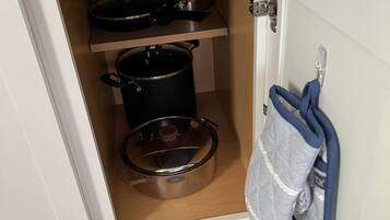 A kitchen with two pots on shelves and a hanging cloth.