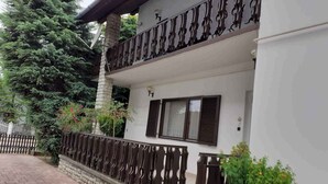 A two-story building with a balcony, stone steps, and a brick pathway. - Holiday home with wifi and air conditioning (Balatonboglár)