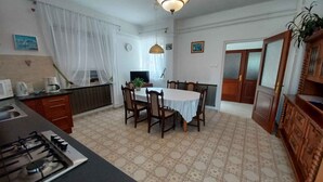 A kitchen with a dining table, chairs, a stove, and a clock on the wall. - Holiday home with wifi and air conditioning (Balatonboglár)