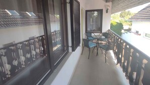 A balcony with a table and chairs, a window with shutters, and a view of the outside. - Holiday home with wifi and air conditioning (Balatonboglár)