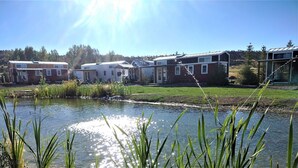 A row of single-story houses with a small pond in the foreground. - Luxury Tiny Home/Base Camp to Ouray, Telluride/3 Queen beds/Washer & Dryer/Smart TV/Hot Tub Access/Patio w/Mountain Views/ Fire Pit/11 mi to Airport (Montrose)