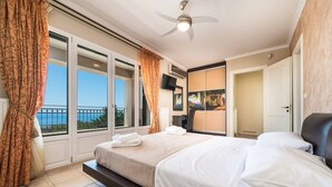 Ein Hotelzimmer mit einem großen Bett, einem Deckenventilator, einem Fernseher und einem Balkon mit Blick.
