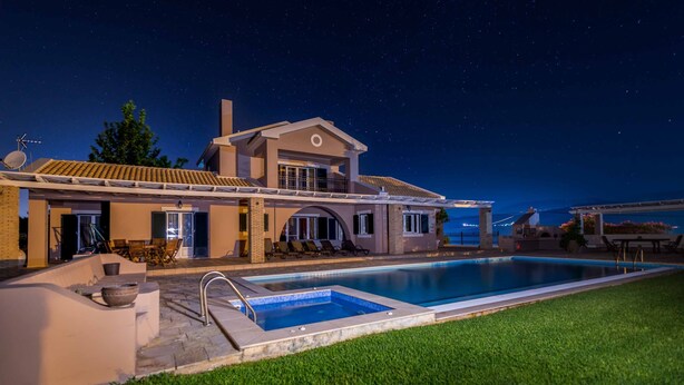 Ein modernes Haus mit Swimmingpool, Sitzgelegenheiten im Freien und einem Sternenhimmel.