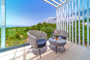 Enjoy breathtaking views of the surrounding mountains from this balcony, featuring a comfortable seating area with a table and vase with fresh flowers.