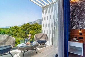 Enjoy breathtaking views of the surrounding mountains from this balcony, featuring a comfortable seating area with a table and vase of fresh flowers.