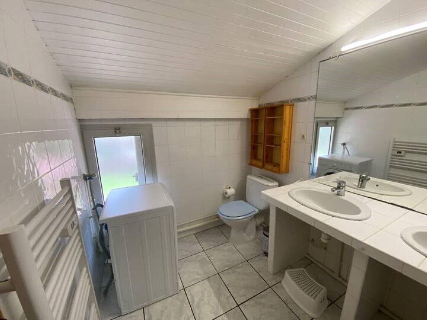 Un baño con dos lavamanos, inodoro, ducha y ventana.