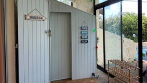 Una stanza con un'ampia porta scorrevole con scritto "MINIZAN", un piccolo ripiano con un cartello che recita "SPIAGGIA DI SABBIA, RELAX, ONDE" e vista su una spiaggia sabbiosa attraverso una porta in vetro.