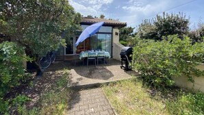 Una piccola casa con un patio, un tavolo con sedie e un barbecue.