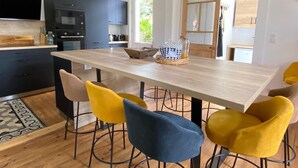 Una cocina moderna con armarios oscuros, encimera de madera y una isla central con taburetes.