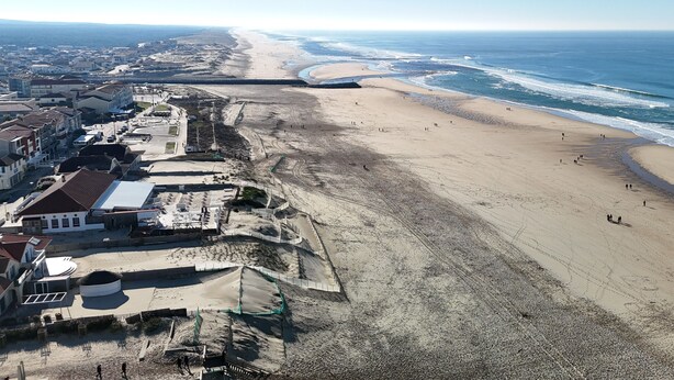 Vista aérea de una playa con paseo marítimo, edificios y muelle.