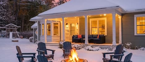 A house with a covered porch, a fire pit, and outdoor seating.