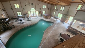 A spacious indoor pool area with a wooden ceiling, multiple windows, and a dining area with tables and chairs. - Cozy lodge with indoor pool, hot tub, loft and more! Great for a close getaway!  (Troy)