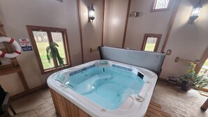 A hot tub with a wooden exterior and a tiled interior, a wooden bench, and a view of a grassy yard through a window. - Cozy lodge with indoor pool, hot tub, loft and more! Great for a close getaway!  (Troy)