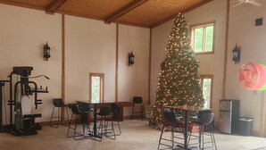 A room with a large Christmas tree, exercise equipment, a dining table with chairs, and a ceiling fan. - Cozy lodge with indoor pool, hot tub, loft and more! Great for a close getaway!  (Troy)