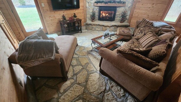 A cozy living room with a stone fireplace, a flat-screen TV, and comfortable seating. - Cozy lodge with indoor pool, hot tub, loft and more! Great for a close getaway!  (Troy)