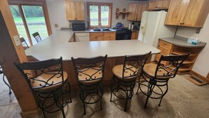 A kitchen with a large island, wooden cabinets, and a dining area with four chairs. - Cozy lodge with indoor pool, hot tub, loft and more! Great for a close getaway!  (Troy)