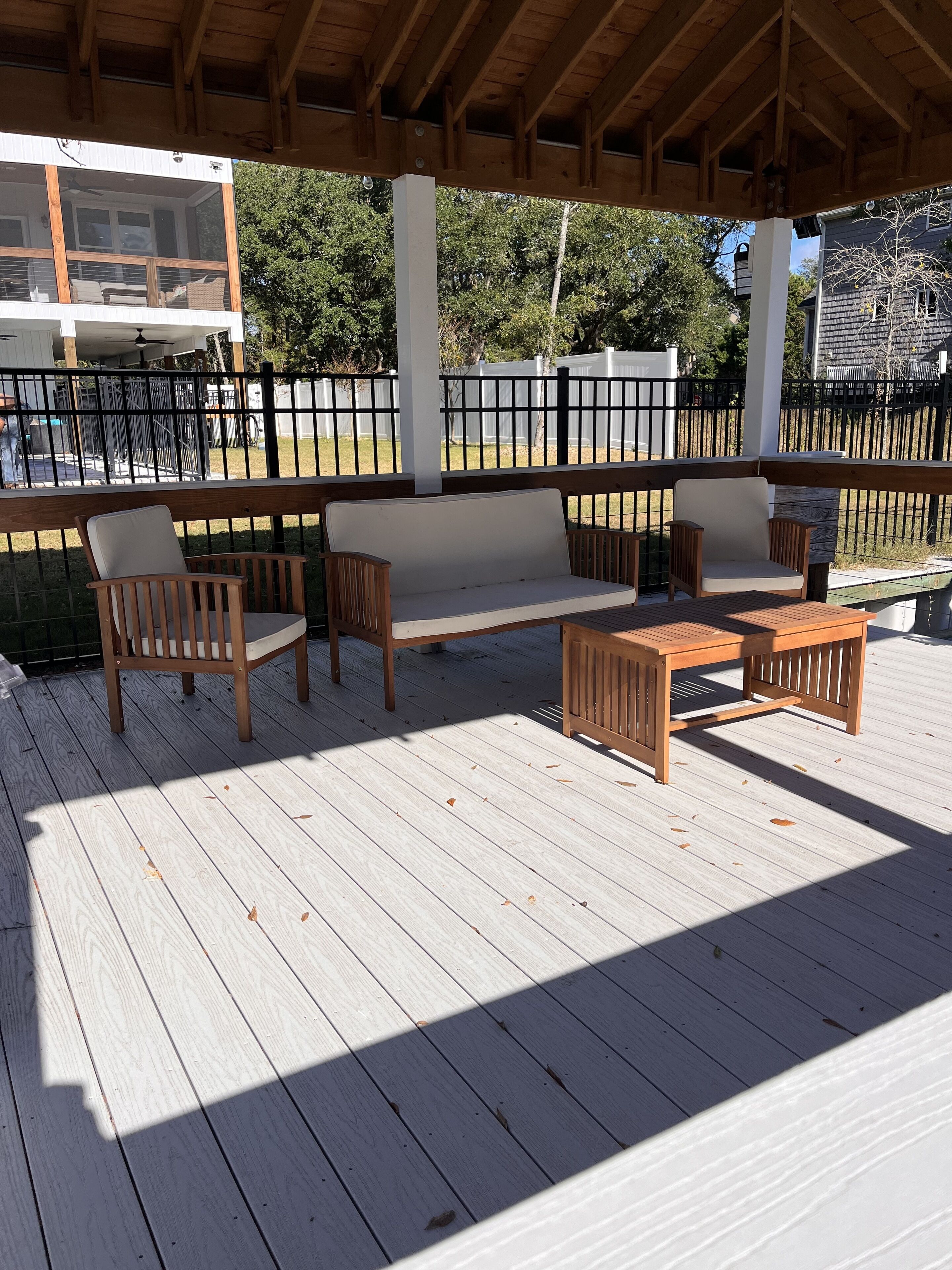 A covered outdoor seating area with wooden furniture and a white railing.
