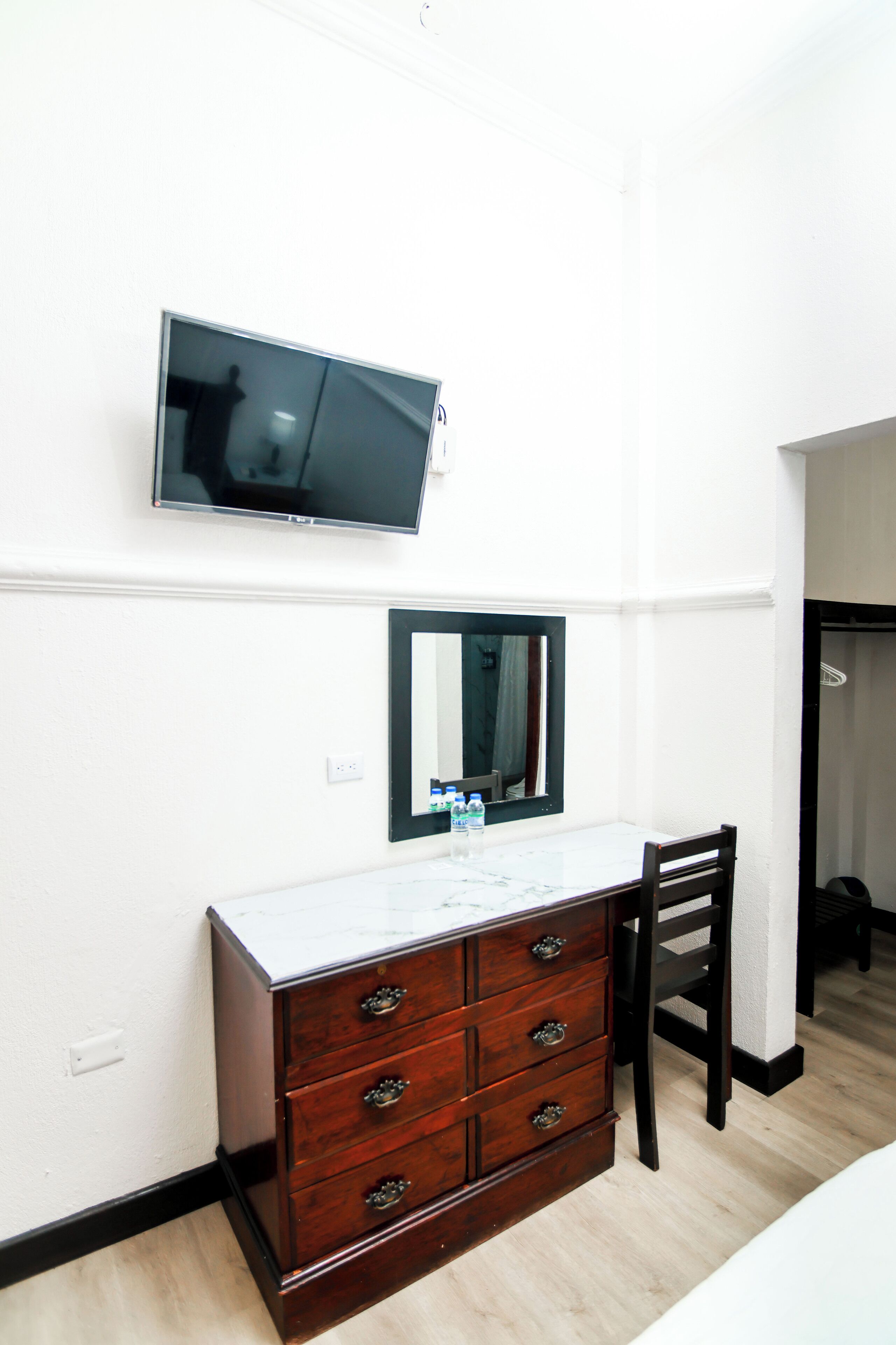 Una habitación de hotel con un aparador de madera, un televisor montado en la pared y un espejo sobre el aparador.