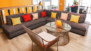 A modern living room with a sectional sofa, a glass coffee table, and a ceiling fan. - Hotel Villa del Lago (Flores)