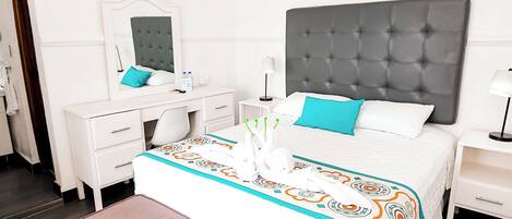 A neatly arranged hotel room with a bed, bedside tables, a mirror, and a ceiling fan.