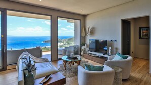 Een moderne woonkamer met een grote televisie, comfortabele zitmogelijkheden en uitzicht op de oceaan.