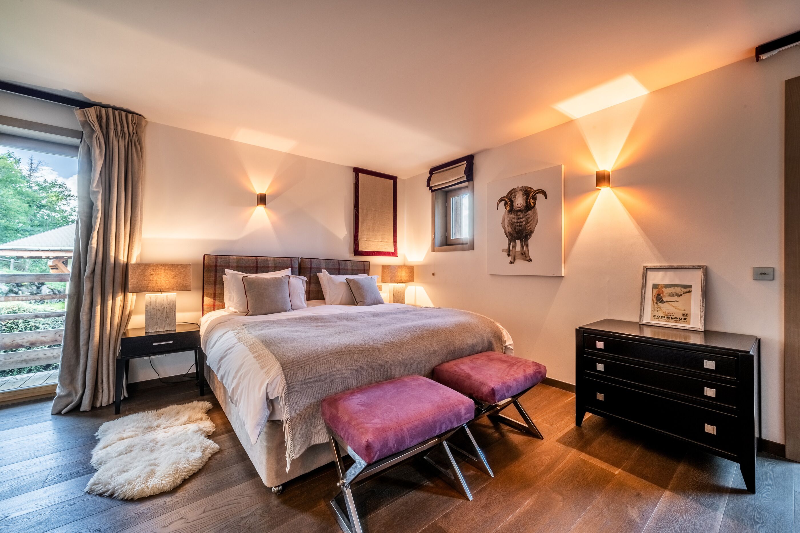 A modern bedroom with a large bed, bedside tables, a dresser, and a window with curtains.