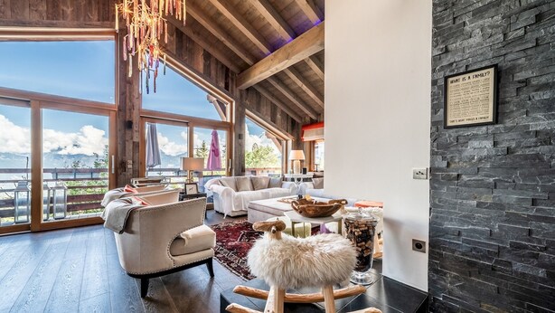 Un salón espacioso con un amplio ventanal, chimenea y vistas a las montañas.