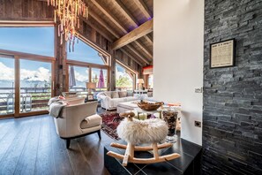 A spacious living room with a large window, a fireplace, and a view of the mountains. - Purdey  - Lovely chalet in Combloux (Combloux)