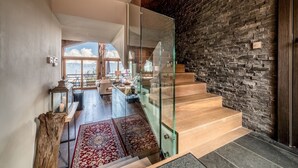 Un interior moderno con una escalera, una pared de piedra y vistas al exterior.