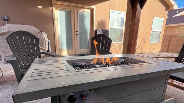 An outdoor patio with a built-in fire pit table, two chairs, and a pergola overhead. - Spacious 4-bedroom house in charming Carlsbad with WiFi and AC (Carlsbad)