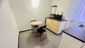A compact kitchen with a small dining table and chairs, a microwave, and a water dispenser on the counter. - Suite Menotti - Sanremo (Sanremo)