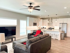 A modern living room with a grey sofa, a TV, and a ceiling fan.