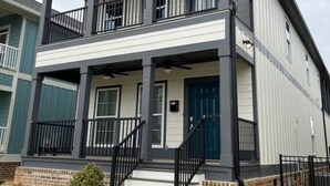 A two-story building with a balcony on the upper floor, a front door, and a set of stairs leading to the entrance.