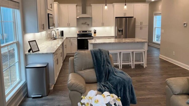 A modern kitchen with white cabinets, a stainless steel refrigerator, and pendant lighting.