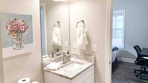 A bathroom with a double sink, a large mirror, and a painting of flowers on the wall.