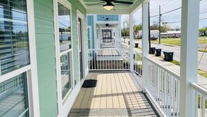 A covered porch with a ceiling fan, wooden flooring, and white railings.