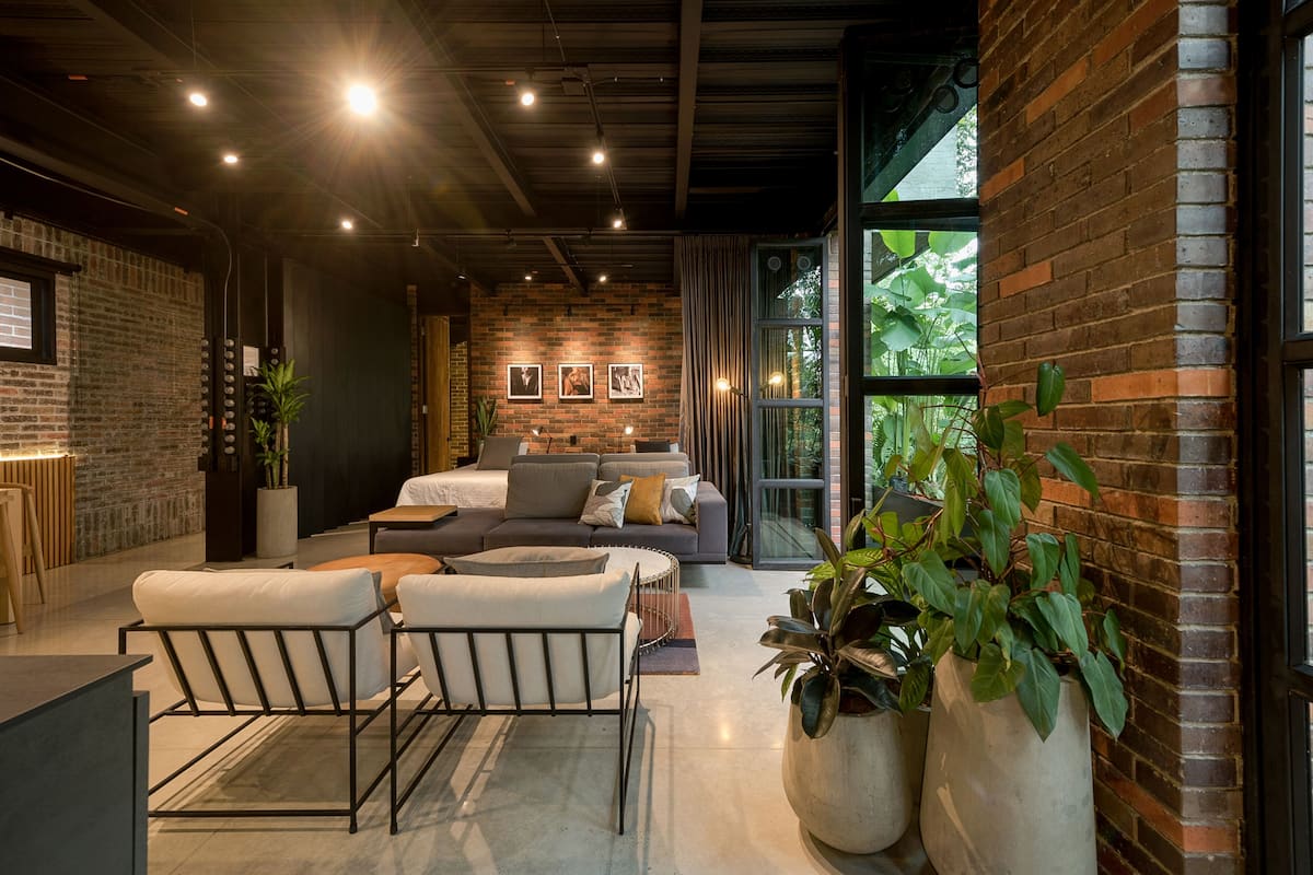 A modern living room with a brick wall, a sofa set, and large windows.