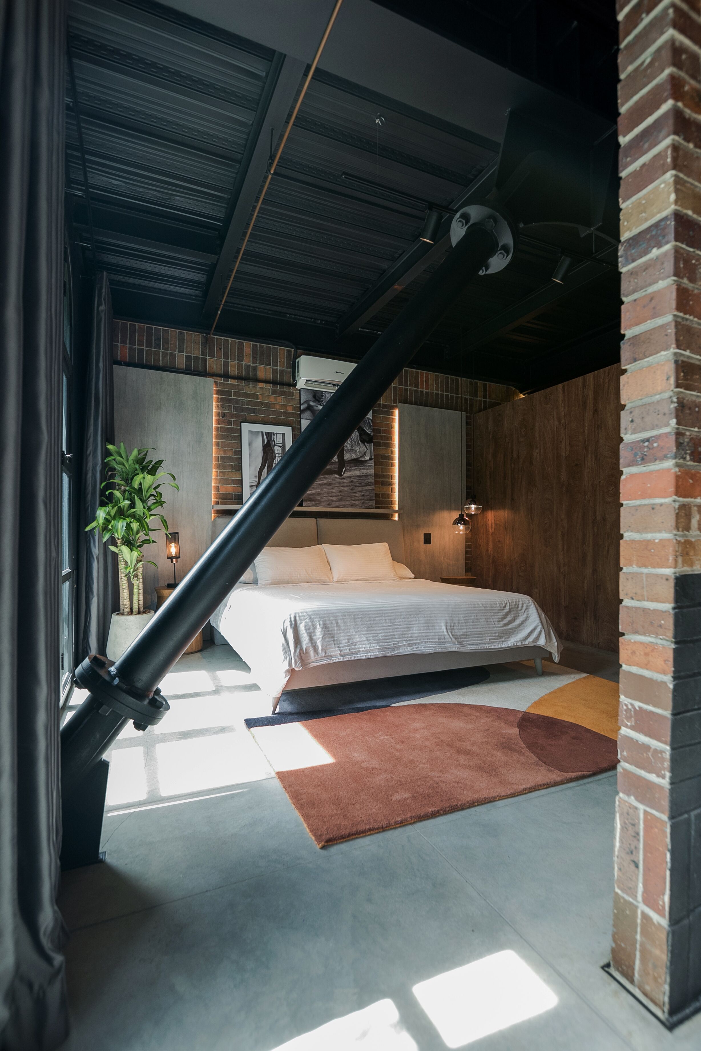 Une chambre à coucher moderne avec un lit, une plante en pot et un mur en briques.