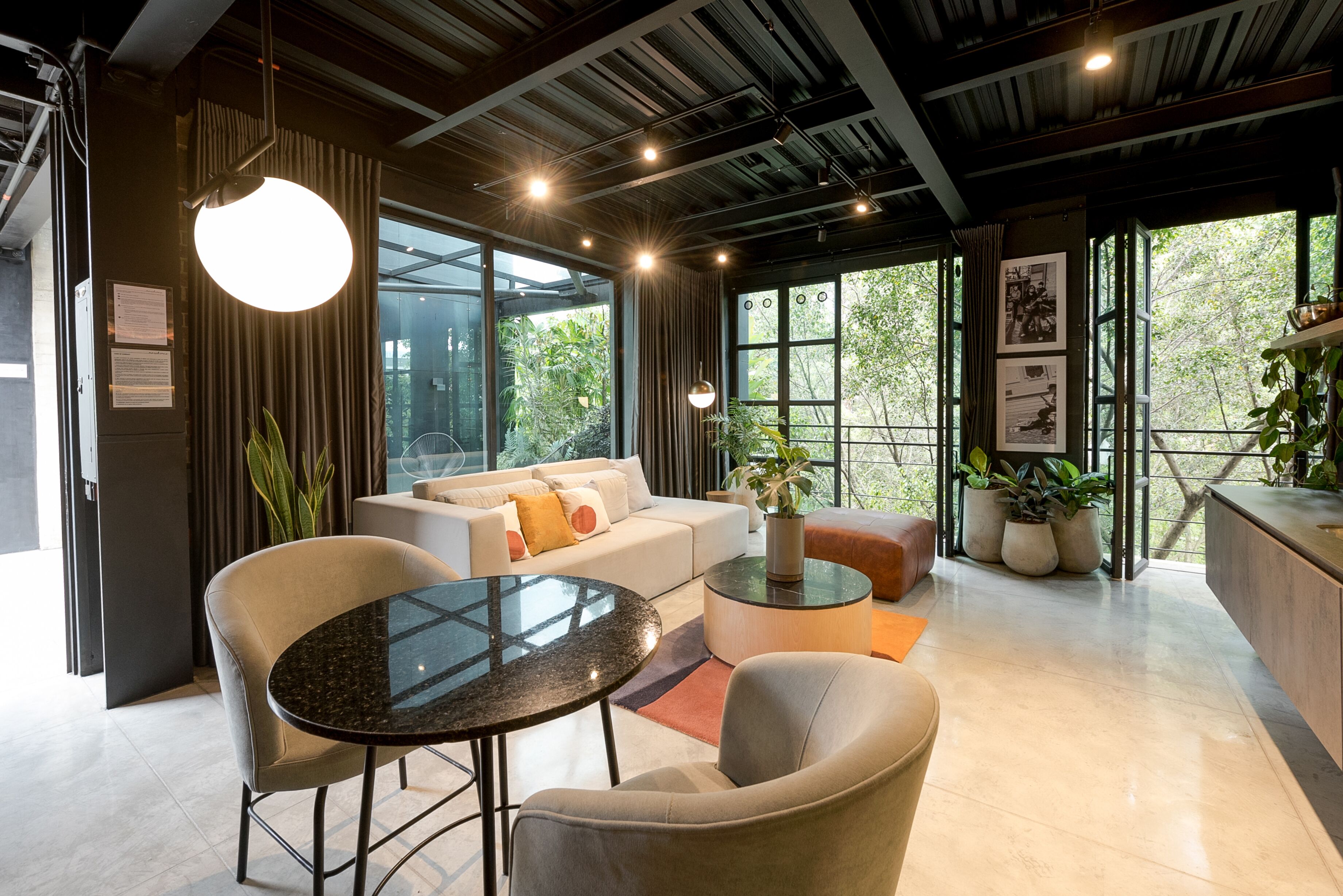 A modern interior with a sofa, round tables, and potted plants.