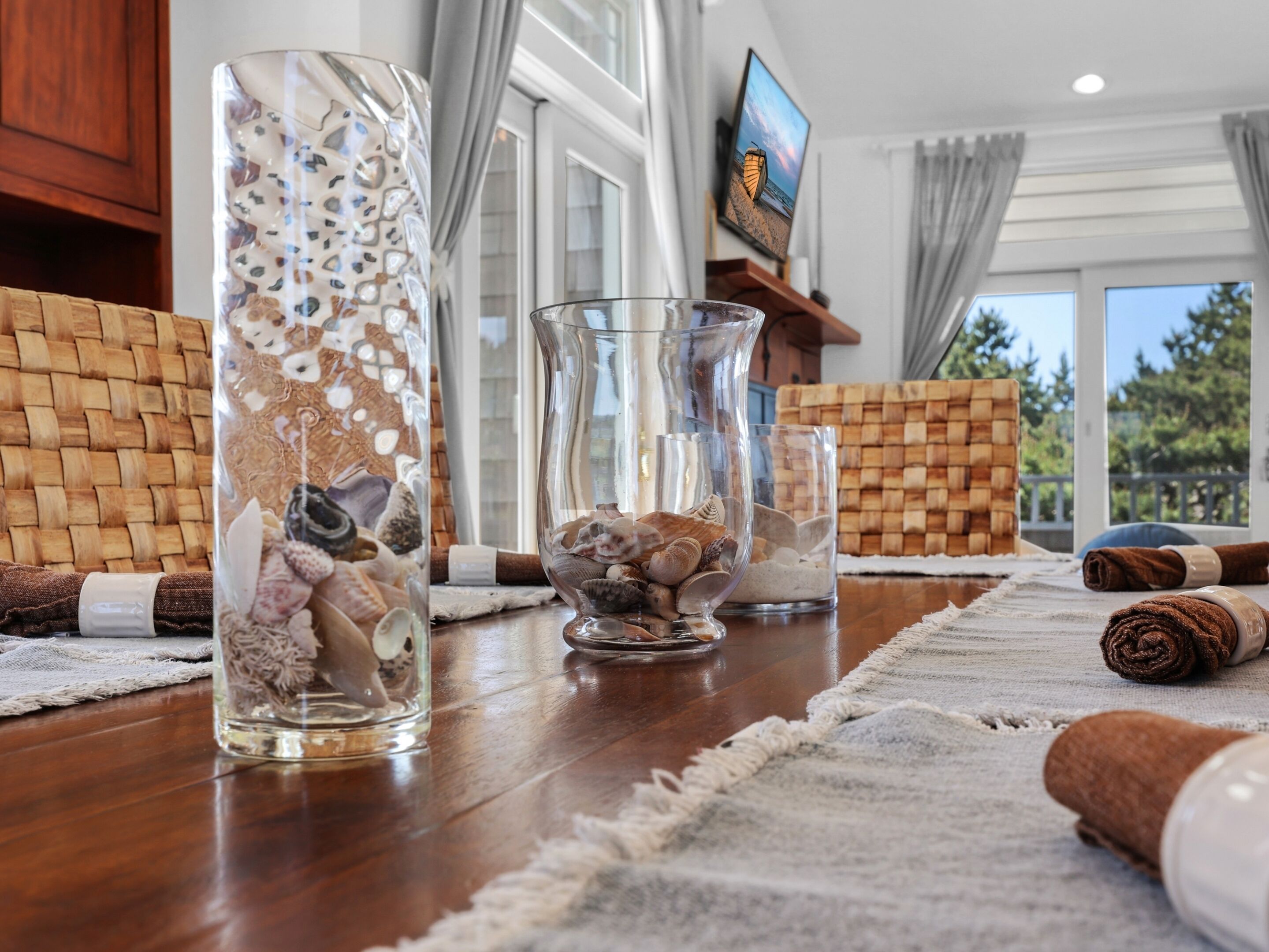 A room with a wooden floor, a television on the wall, and a view of the outdoors.