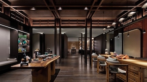 Un intérieur moderne avec un comptoir d’accueil central en bois, un espace détente doté de fauteuils confortables et un plafond orné de motifs.