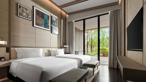 Une chambre d’hôtel moderne avec deux lits, un téléviseur à écran plat et un balcon offrant une vue sur la verdure.