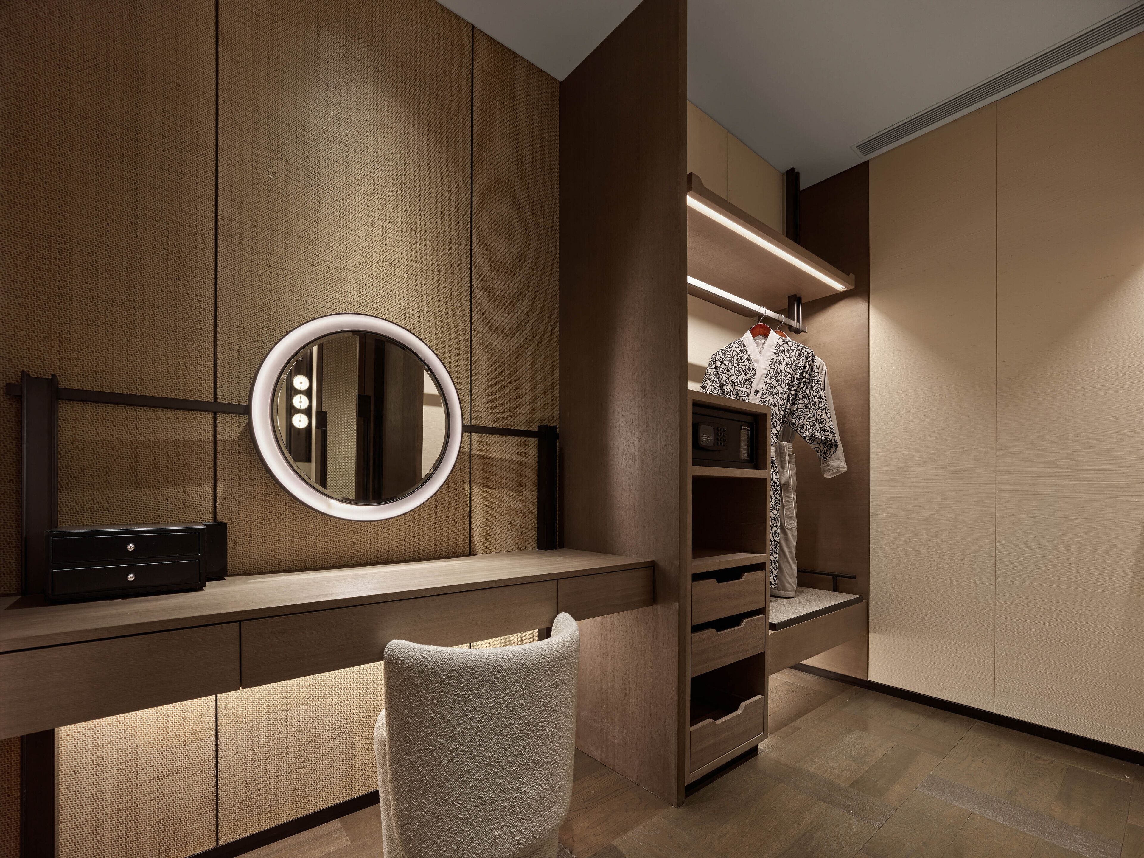 Un meuble-lavabo moderne doté d’un miroir rond, d’une table de toilette et d’une armoire intégrée avec un espace pour suspendre des vêtements.