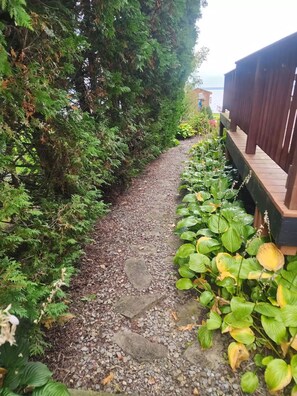 A gravel pathway flanked by dense foliage and a wooden deck. - Oneida Lake Oasis (Bridgeport)