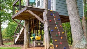 A wooden play structure with a climbing wall and swings. - Mountain Veiws, Hot Tub,Treehouse,Gameroom, Child playroom, pet friendly  (Verona)