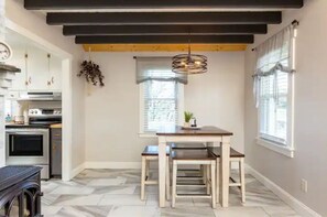 A kitchen with modern appliances, a dining area with a wooden table and benches, and a hanging light fixture. - Luxury Farm Cottage, Hot Tub, Sauna,Massage,Shenandoah Views, pet friendly (Weyers Cave)