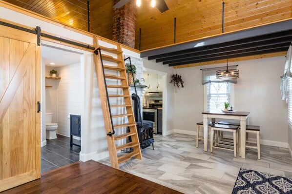 A modern kitchen with a black stove, wooden cabinets, and a hanging plant. - Luxury Farm Cottage, Hot Tub, Sauna,Massage,Shenandoah Views, pet friendly (Weyers Cave)