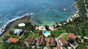 Vista aérea de una zona residencial costera con casas, piscina y un litoral rocoso.