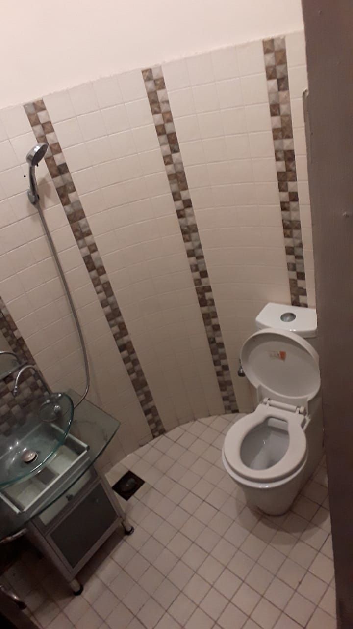 A bathroom with a toilet, a glass sink, and a shower.